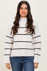 woman wearing a white and black striped oversized sweater with a high neck and long sleeves