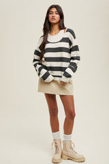 woman wearing a black and white striped oversized sweater paired with a beige mini skirt and tan chunky boots