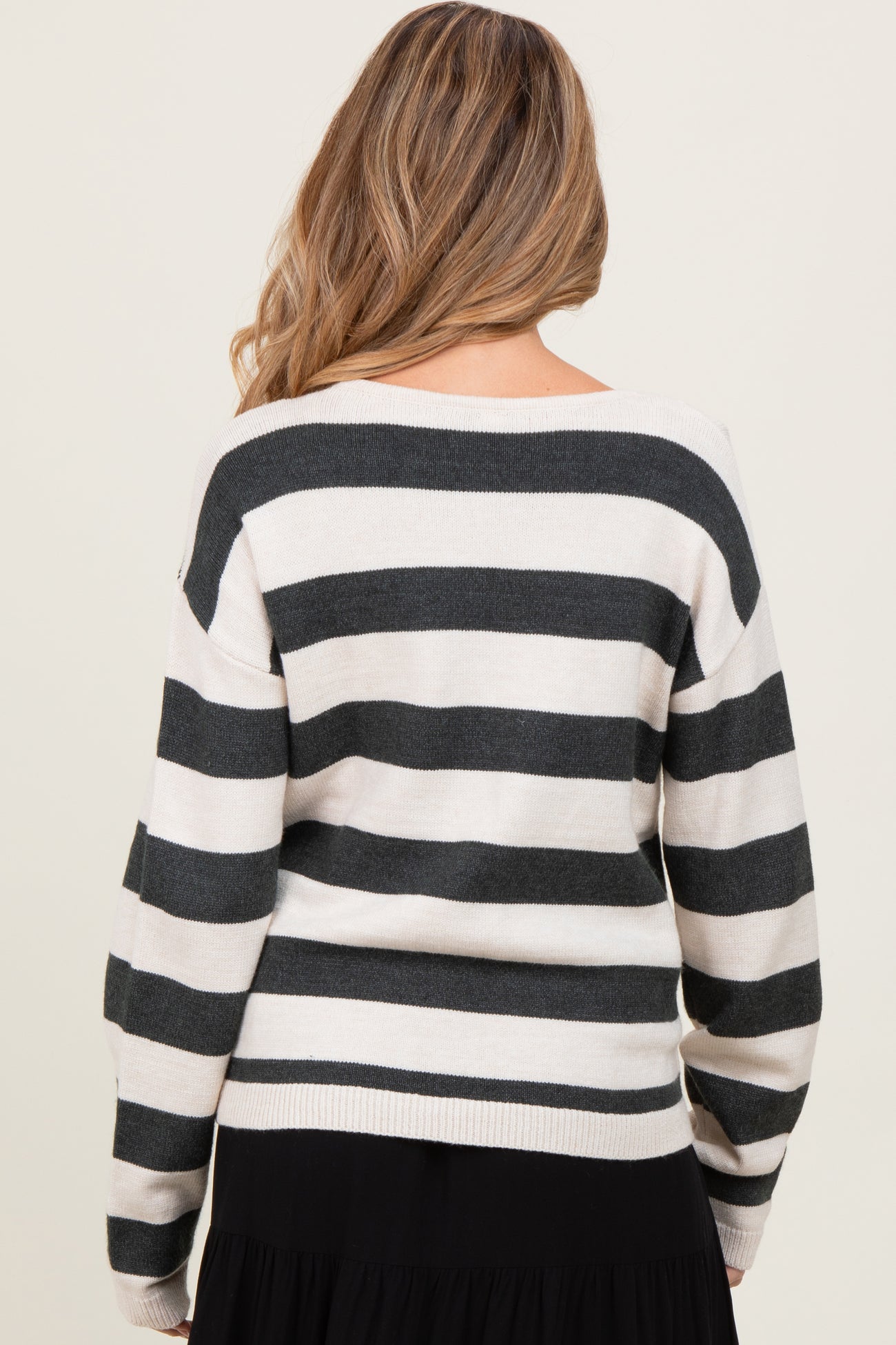 woman wearing a striped maternity sweater in cream and black, seen from the back