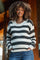 woman wearing a black and white striped maternity sweater with a visible baby bump and casual blue jeans