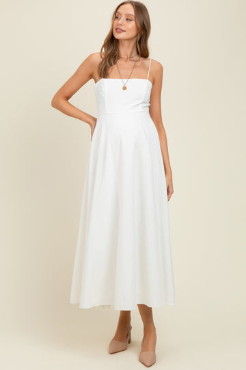 woman wearing a white maternity dress with a square neckline and flowy skirt, showcasing her baby bump
