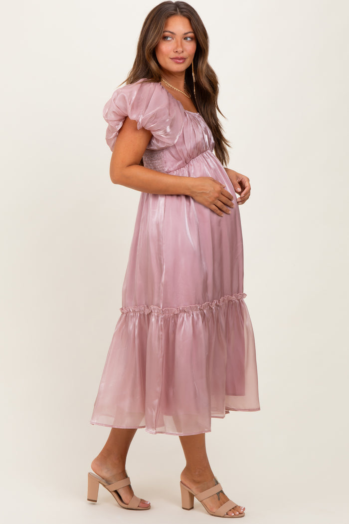 woman wearing a light mauve puff sleeve maternity dress with a ruffled hem and baby bump visible