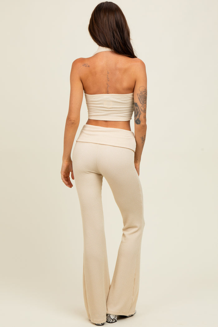 woman wearing a beige ribbed two-piece set with a cropped halter top and flared pants, seen from the back