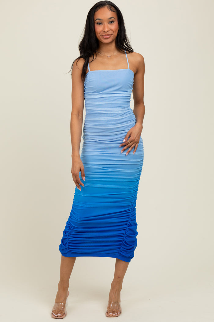 woman wearing a blue ombre ruched midi dress with adjustable spaghetti straps