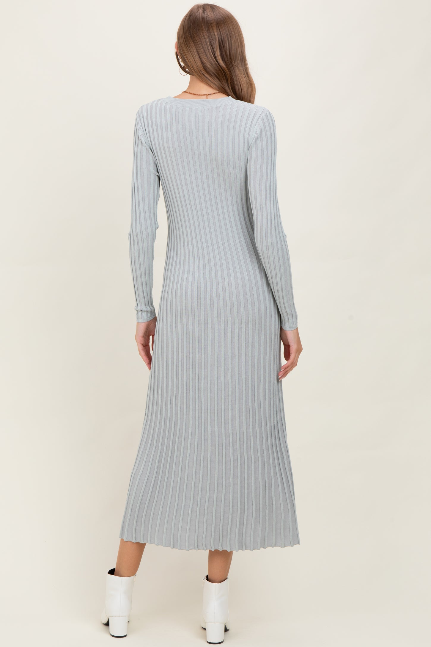 woman wearing a light gray ribbed maternity dress with long sleeves, showing back view and ankle-length silhouette