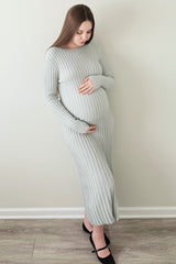 woman wearing a light gray ribbed maternity dress and gently cradling her baby bump