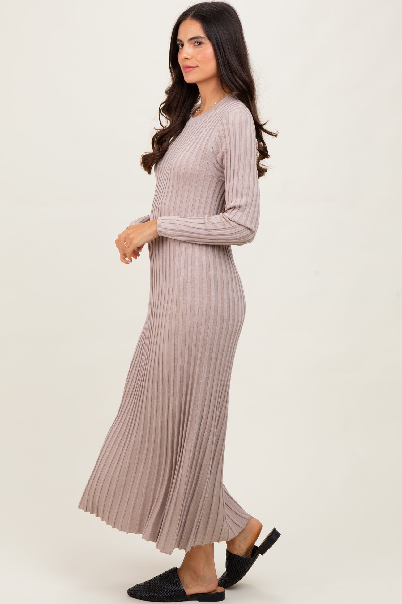 woman wearing a beige ribbed long sleeve maxi dress with a flared skirt and open-toe black sandals