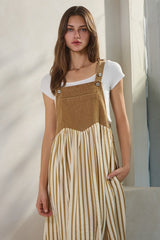 woman wearing a tan corduroy and striped long dress with buttons and pockets over a white t-shirt
