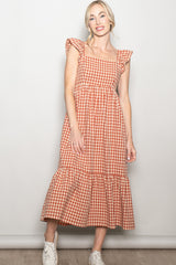 woman wearing a rust and cream gingham midi dress with ruffle sleeves and a tiered skirt