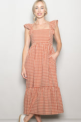 woman wearing a rust and cream checkered maxi dress with ruffled sleeves and pockets