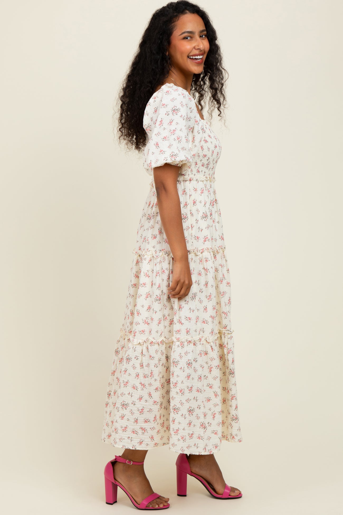 woman wearing a white floral midi dress with puff sleeves and tiered skirt, paired with pink high heel sandals
