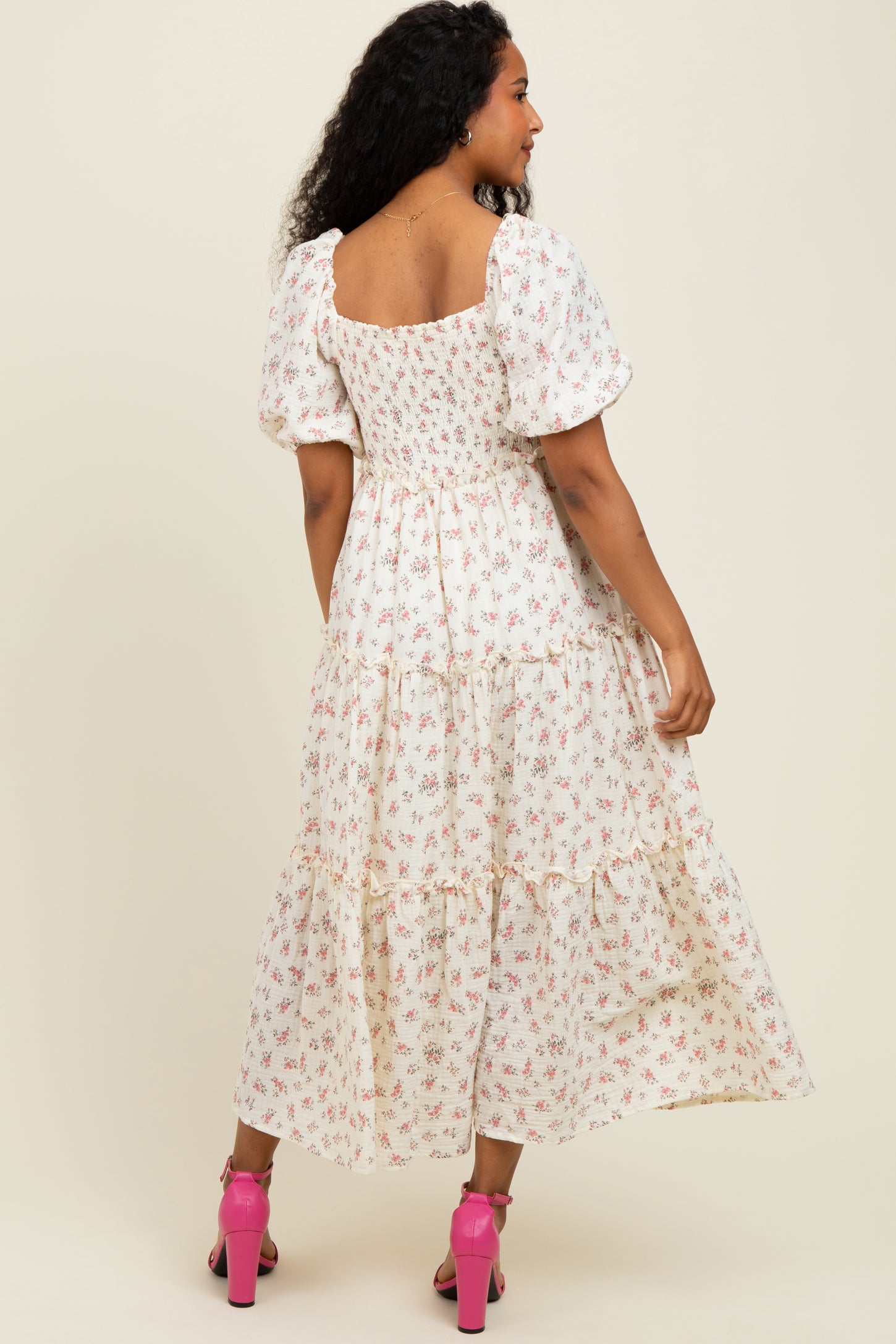 woman wearing a white floral maxi dress with puff sleeves and a tiered skirt