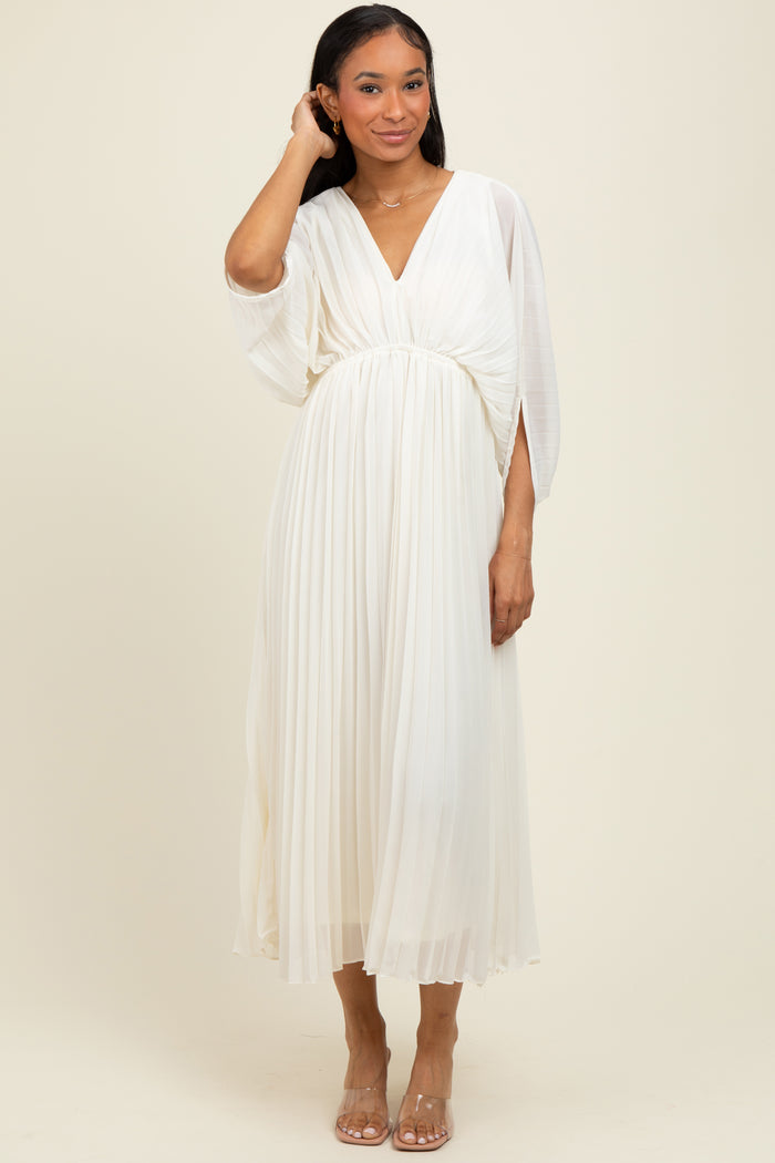 woman wearing a flowing white pleated midi dress with a deep v-neck and batwing sleeves