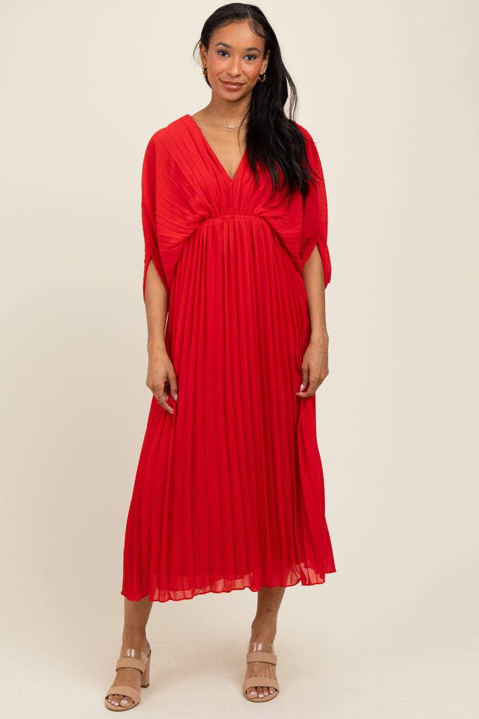 woman wearing a red pleated midi dress with a v-neck and cape sleeves