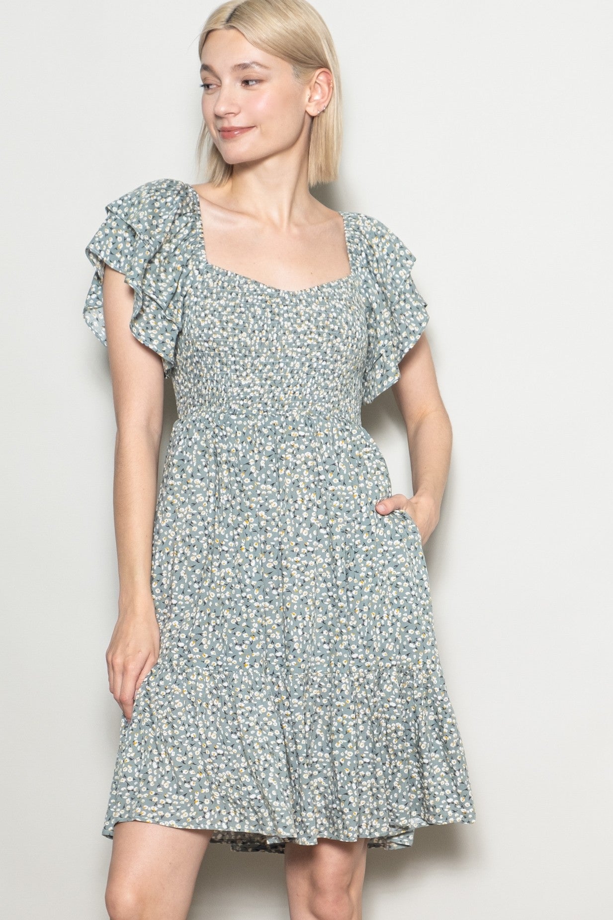 woman wearing a green floral short sleeve dress with ruffle details and a cinched waist
