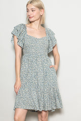 woman wearing a green floral short sleeve dress with ruffle details and a cinched waist