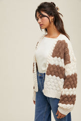 woman wearing a cream and brown patterned knit cardigan over a white top with high-waisted blue jeans