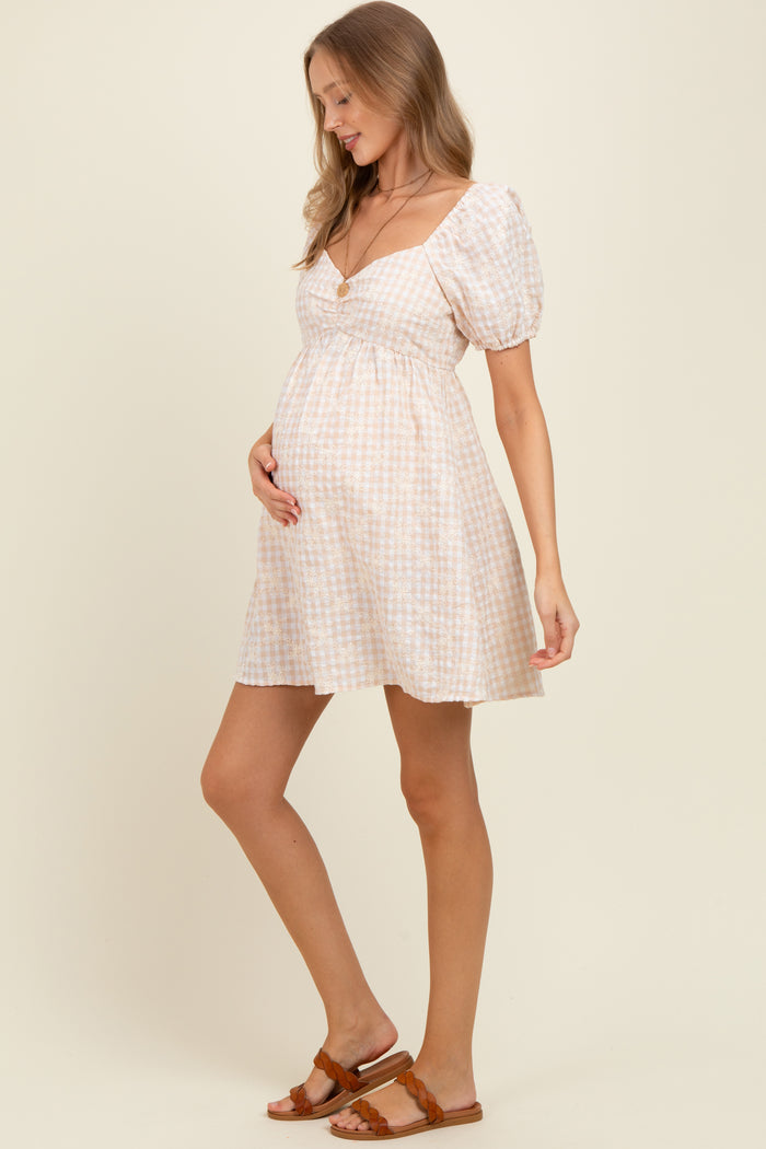 woman wearing a light pink and white checkered maternity dress with puff sleeves and a baby bump visible
