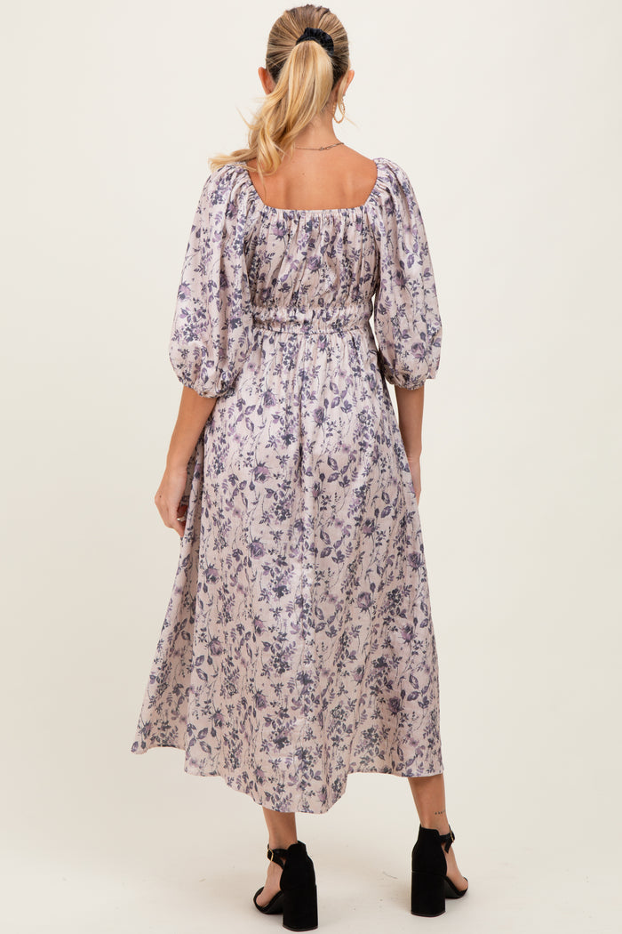 woman wearing a floral print maternity maxi dress with puffed sleeves, showing a comfortable fit around the baby bump