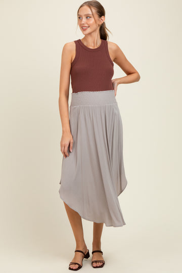 woman wearing a maroon tank top and a light gray maternity skirt with a smocked waistband
