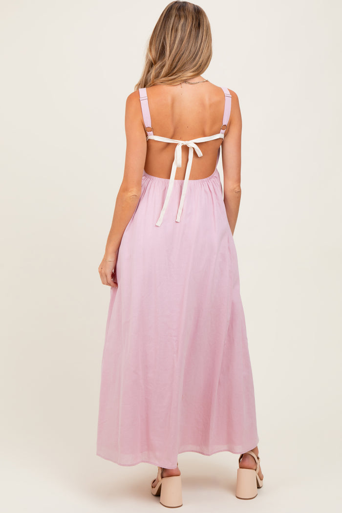 woman wearing a pink backless maternity maxi dress with tie straps, showcasing a flowing silhouette
