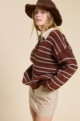 woman wearing a brown and white striped sweater with a collar and beige shorts, styled with a brown bucket hat