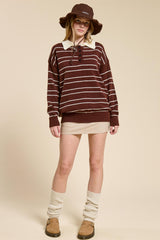 woman wearing a burgundy and white striped oversized sweater, tan mini skirt, and a brown bucket hat with knee-high cream socks