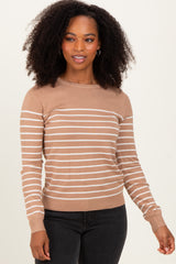 woman wearing a tan striped sweater with long sleeves and ribbed cuffs, styled with black jeans