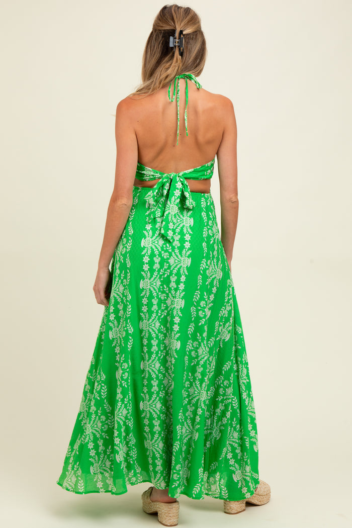 woman wearing a green floral maternity maxi dress with open back and halter neckline