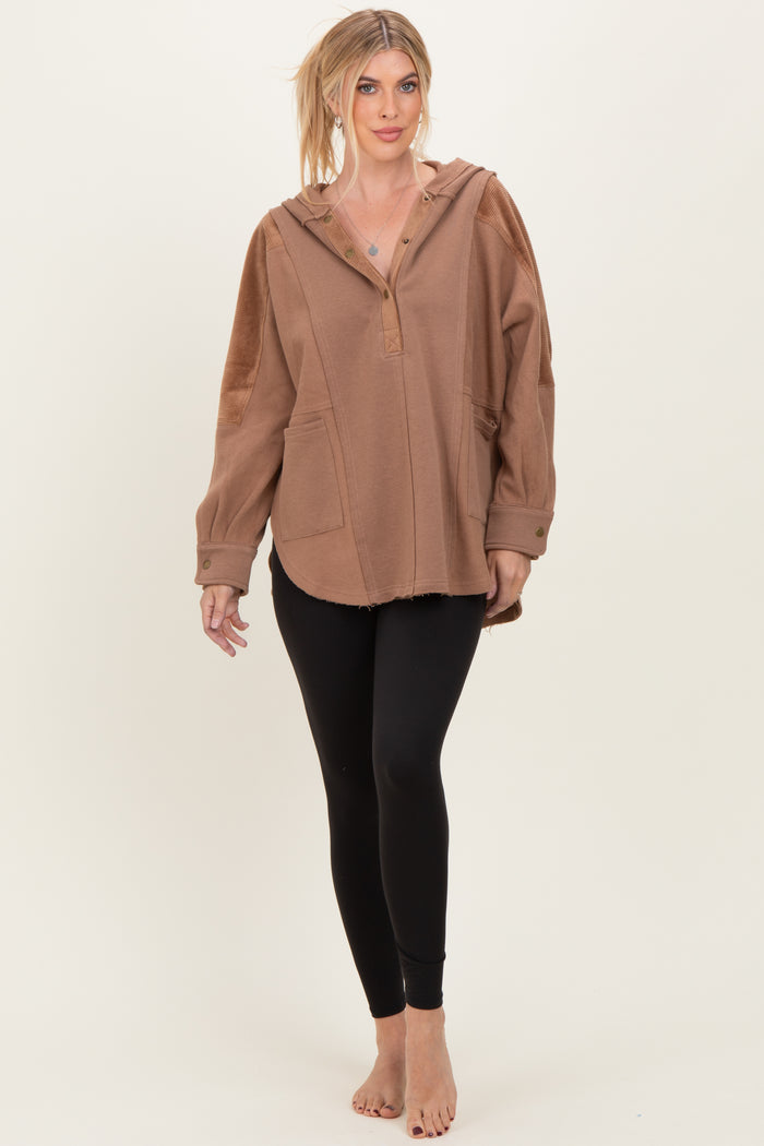 woman wearing a brown oversized hoodie with a hood and front pockets, paired with black leggings