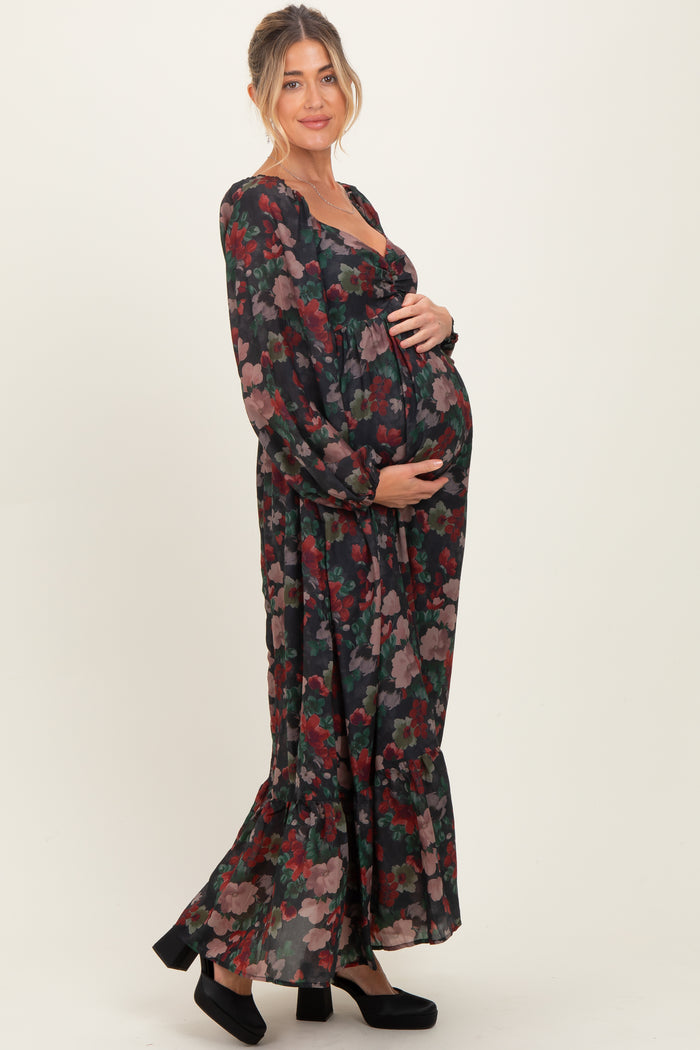 woman wearing a black floral long sleeve maternity dress and holding her baby bump