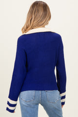 woman wearing a navy blue maternity sweater with white striped details on the sleeves and a relaxed fit