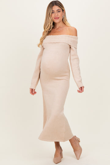 woman wearing a beige off-the-shoulder maternity dress with long sleeves and embellished neckline, showing her baby bump