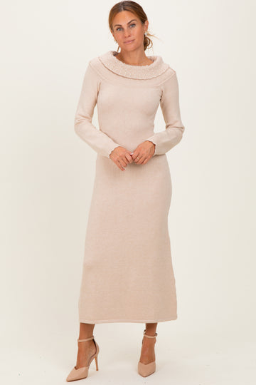woman wearing a light beige long sleeve sweater dress with a high cowl neck and a fitted silhouette