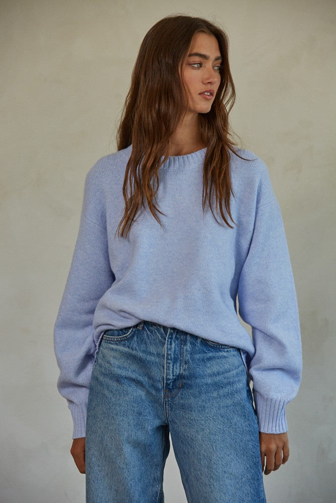 woman wearing a light lavender oversized sweater and high-waisted blue jeans
