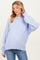 woman wearing a light purple oversized maternity sweater with long sleeves and ribbed hem, posing gently with her hand on her neck