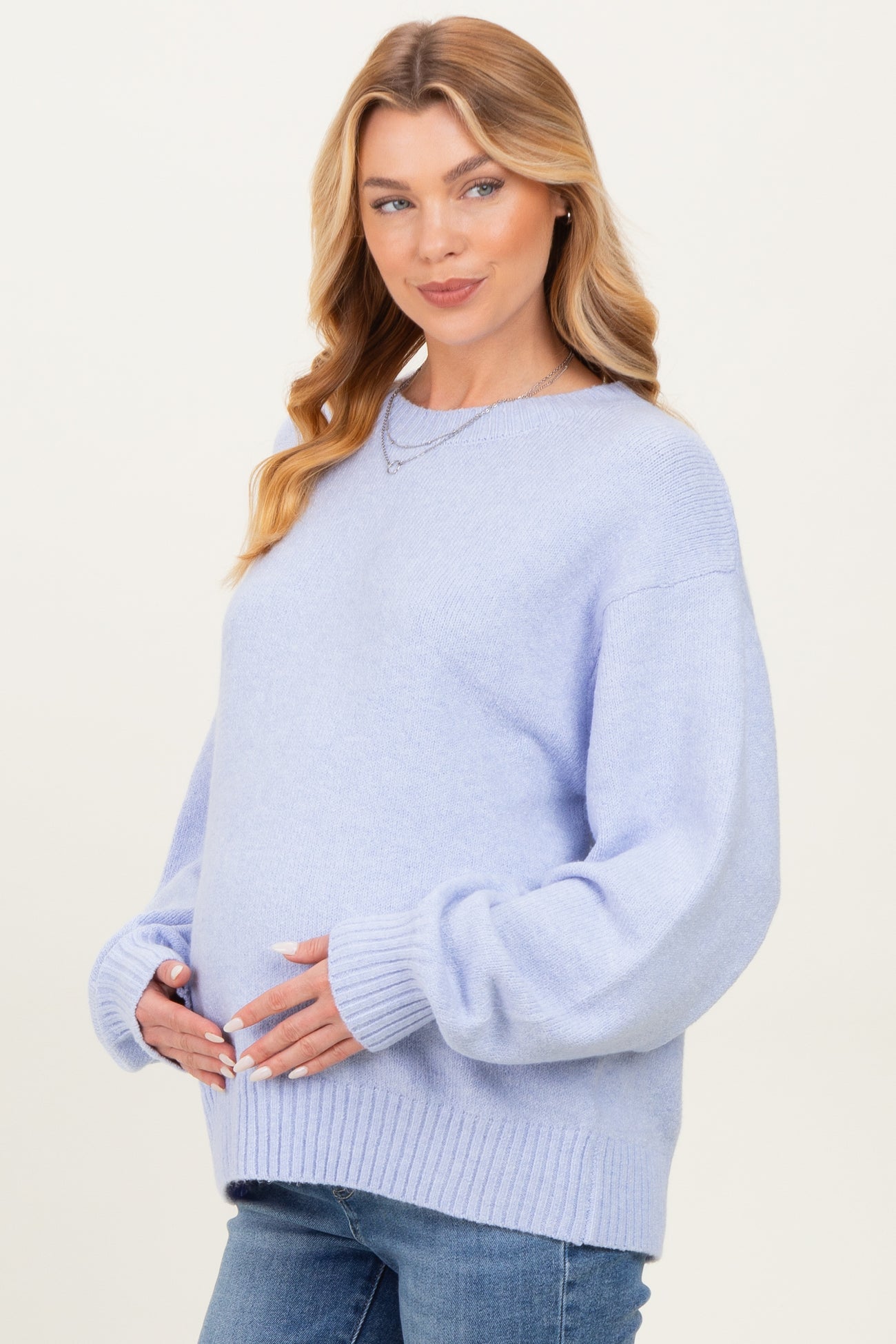 woman wearing a light blue maternity sweater with balloon sleeves and holding her baby bump