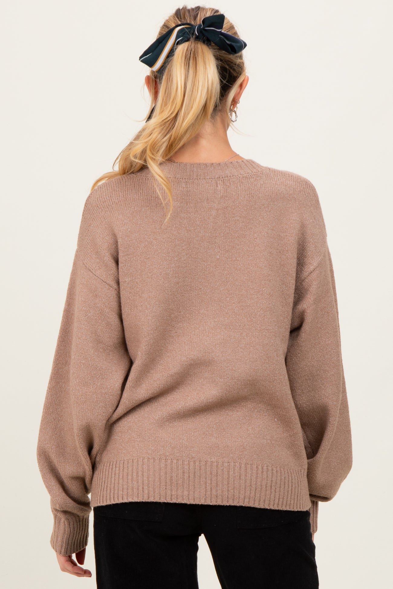 woman wearing a taupe oversized maternity sweater with long sleeves and ribbed hem, showing the back view