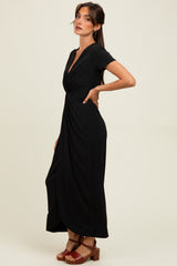 woman wearing a black short sleeve maxi dress with a twisted front detail and red heeled sandals