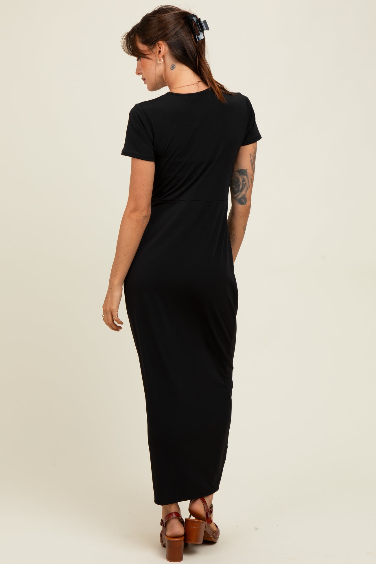 woman wearing a black short sleeve maxi dress, showing the back view and styled with brown heeled sandals
