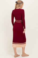 woman wearing a burgundy ribbed long sleeve dress with a beige striped hem and back detail