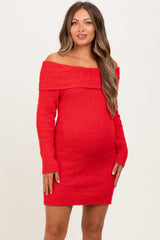 woman wearing a red off-the-shoulder knitted maternity dress with a fitted silhouette and long sleeves, showcasing her baby bump