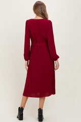 woman wearing a burgundy long sleeve maternity dress with a belt, view from the back