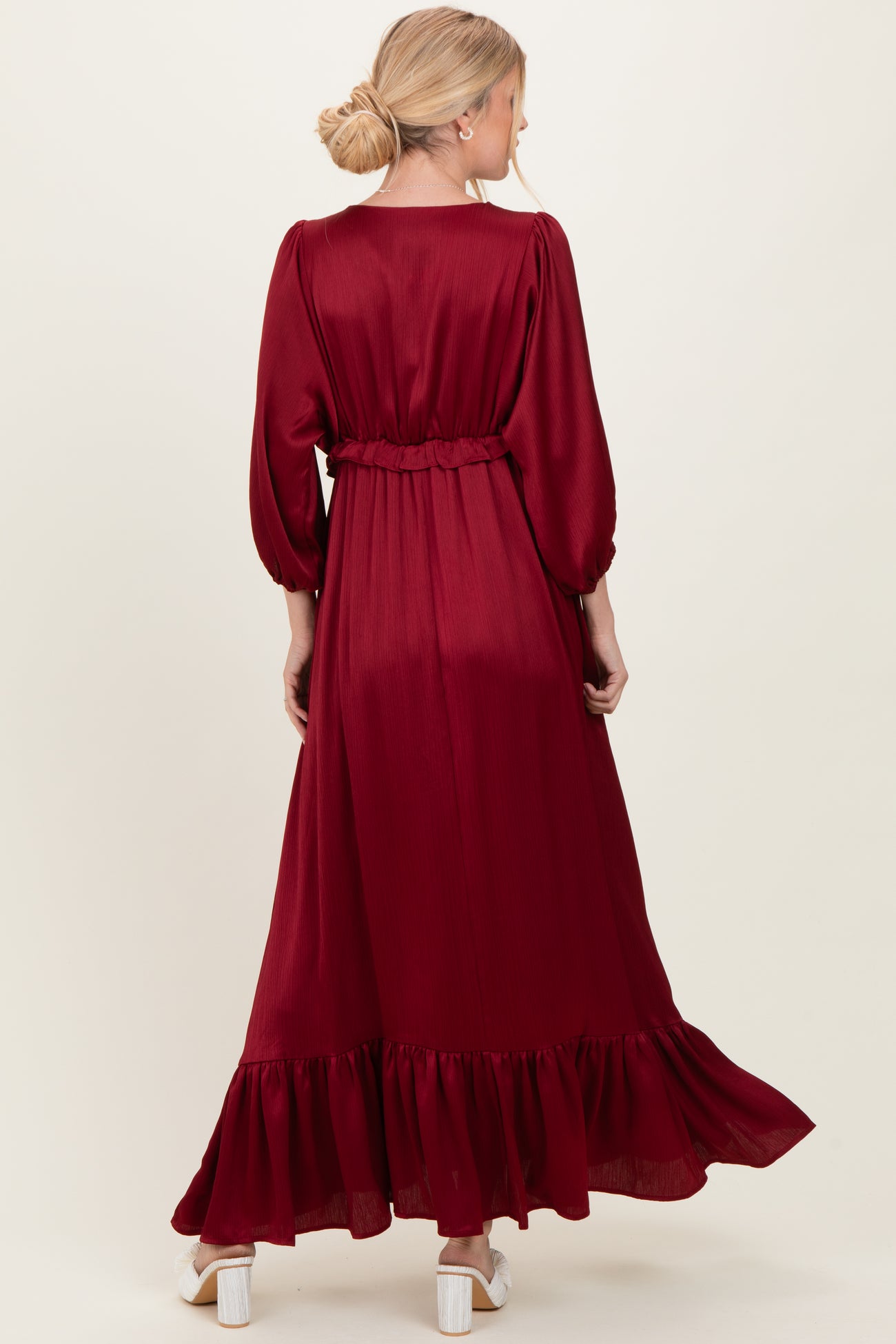 woman wearing a burgundy long sleeve maxi dress with a cinched waist and ruffled hem