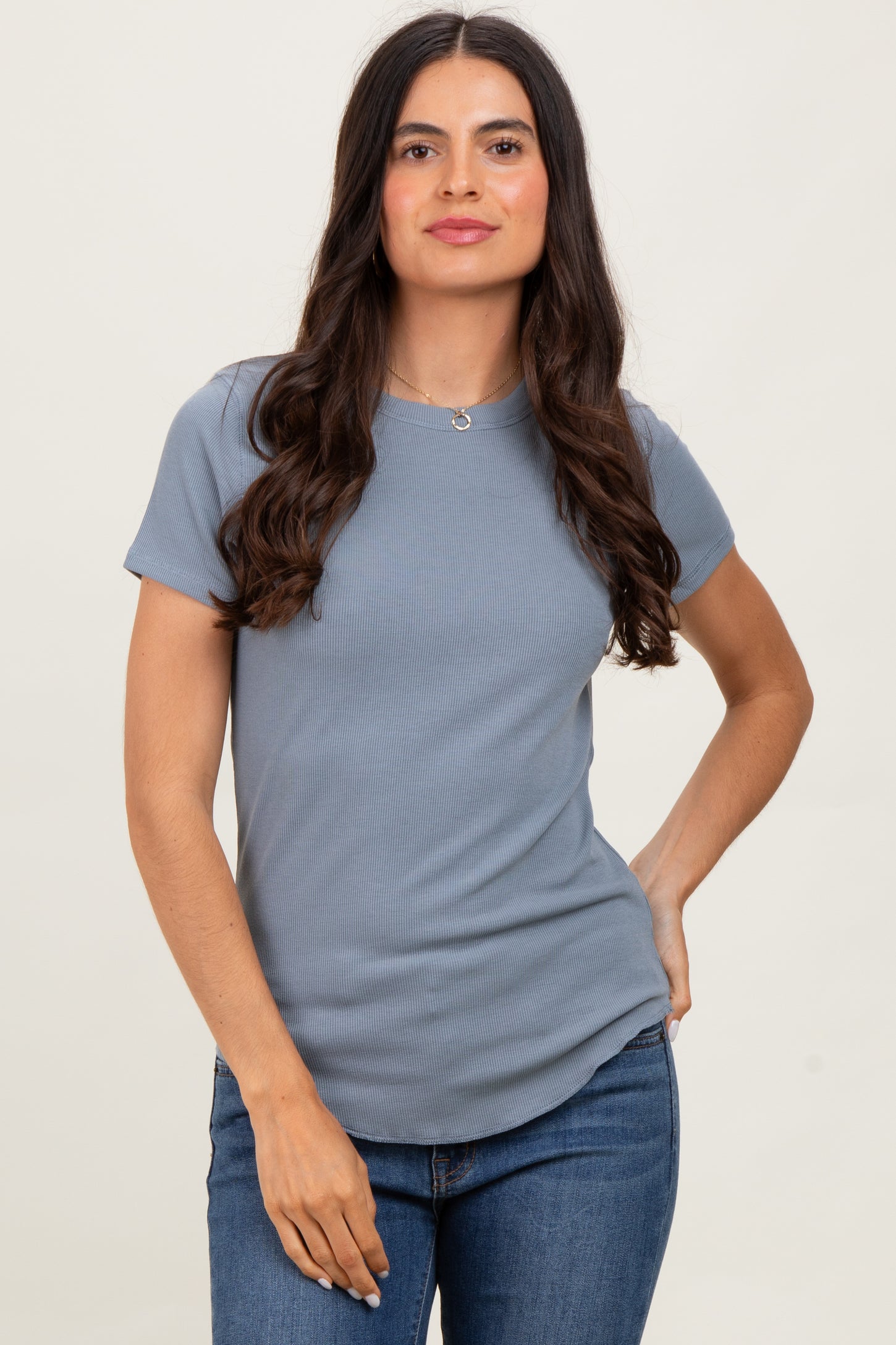 woman wearing a light blue ribbed short sleeve top and blue jeans with a casual pose