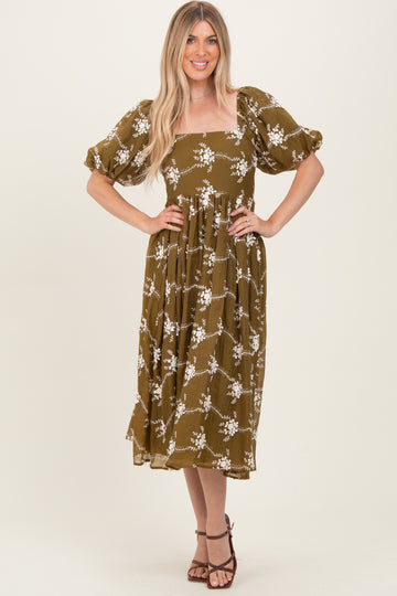 woman wearing an olive green floral midi dress with puff sleeves and a square neckline