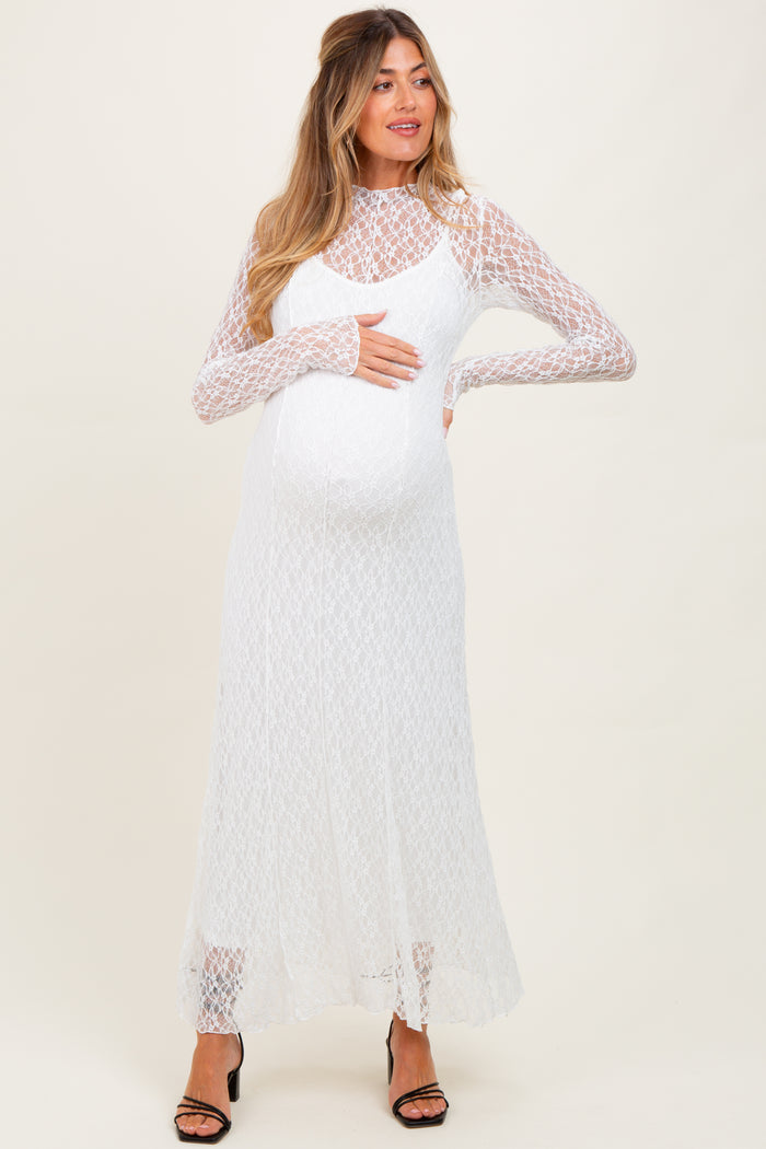 woman wearing a white lace long sleeve maternity dress and holding her baby bump