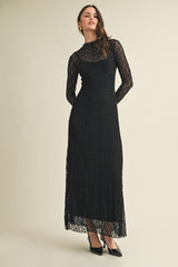 woman wearing a black lace long sleeve maxi dress with a high neckline and fitted silhouette