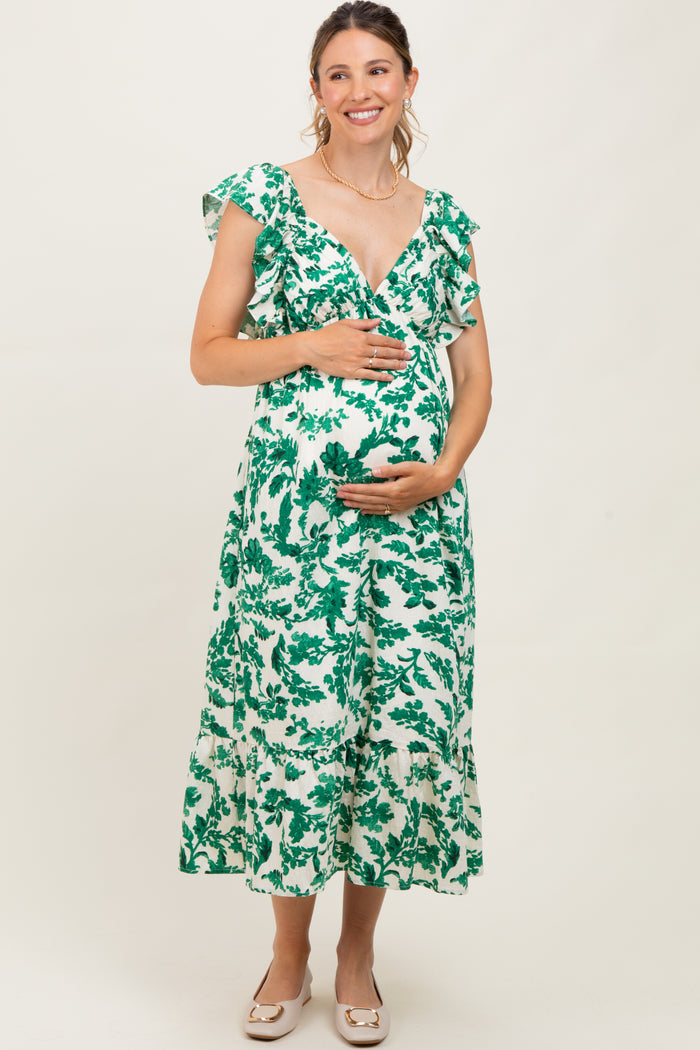 woman wearing a green and white floral maternity dress with ruffled sleeves and a baby bump