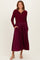 woman wearing a burgundy ribbed sweater with a collared neckline and a pleated midi skirt with pockets